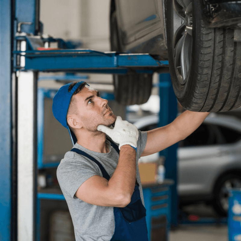mechanic checking underside of car